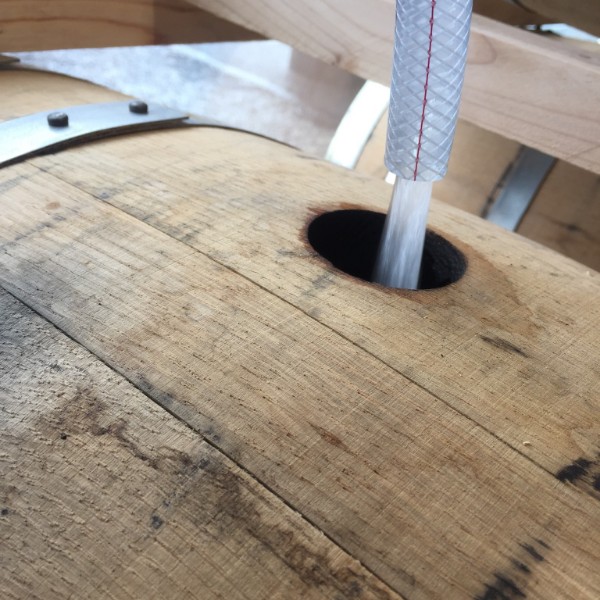 close up of white whiskey distilling into barrels