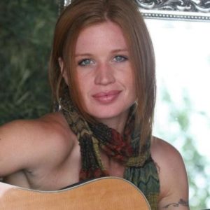 Red haired woman smiling with a guitar